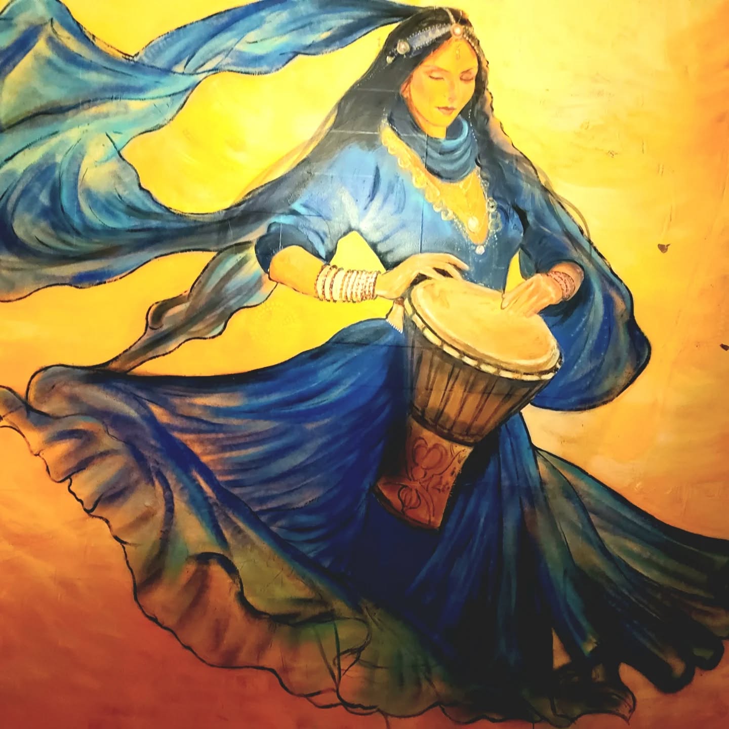 Toile femme en sari bleu jouant du djembé